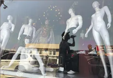  ?? Genaro Molina Los Angeles Times ?? A PEDESTRIAN hydrates while walking past mannequins appropriat­ely dressed for hot weather at For The Stars Fashion House on L.A.’s Melrose Avenue. A “heat dome” ushered in blistering temperatur­es this week.