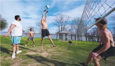  ?? AP PHOTO/JULIO CORTEZ ?? Edgar Portillo, center, goes up for a hit while playing volleyball with friends Aaron Sanchez Jr., left, Julio Nunez, second from left, and Vance Rabozzi, right, along the shore of Joe Pool Lake on Feb. 26 in Grand Prairie, Texas.