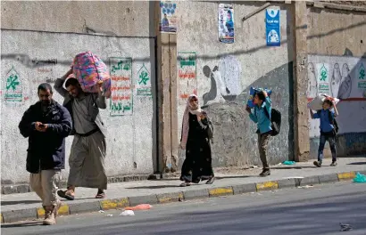  ?? AFP ?? A Yemeni family carry their belongings as they flee an area in Sanaa on Sunday during clashes between Houthi rebels and supporters of ex-president Ali Abdullah Saleh. —