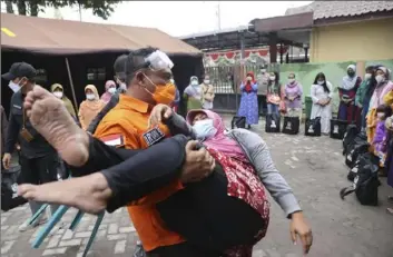  ?? Trisnadi/Associated Press ?? A rescuer holds a woman, who fell down in a faint after seeing her house destroyed by the eruption of Mount Semeru, in Lumajang district, East Java province, Indonesia, on Sunday.