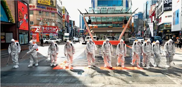  ?? AP ?? south korean army soldiers wearing protective suits spray disinfecta­nt to prevent the spread of the COViD-19 on a street in Daegu, south korea, on thursday —