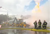  ?? Santiago Mejia / The Chronicle ?? Firefighte­rs battle shooting flames after a gas-line explosion at Geary Boulevard and Parker Avenue, as PG&amp;E workers dig up the ground with hand shovels to reach the damaged pipe Wednesday.