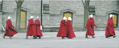  ?? DAVID BEBEE WATERLOO REGION RECORD ?? Actors dressed in the show’s signature red cloaks cross a parking lot in front of Wesley United Church in Cambridge.
