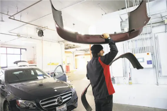  ?? Lea Suzuki / The Chronicle ?? Technician Julio Saucedo carries parts through the George V. Arth & Son body shop in Oakland. The shop has adopted new technology as the industry changes.