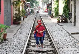  ?? — AFP ?? A boy wearing a spiderman costume stands on Hanoi’s popular train street on Thursday following a municipal authoritie­s order to deal with cafes and ‘ensure safety’ on the railway track.