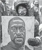  ?? JIM MONE/ AP ?? A protester carries a George Floyd portrait during a march in Minneapoli­s on Monday near a courthouse where a former officer faces trial.