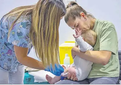  ?? DANIEL GONZÁLEZ (EFE) ?? Una enfermera vacuna a un bebé en brazos de su madre.