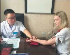  ?? PROVIDED TO CHINA DAILY ?? Zha Minghui takes a Russian patient’s pulse at Suifenhe People’s Hospital in Mudanjiang.