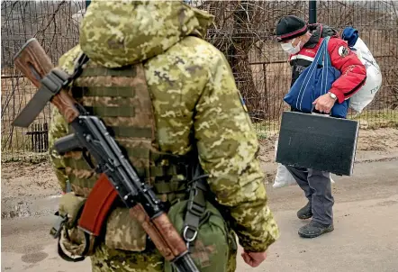  ?? AP ?? An elderly man crosses from a pro-Russian separatist-controlled area to Ukrainian government-controlled territory in Stanytsia Luhanska, eastern Ukraine. The chill of a Cold War is hanging over Eastern Europe again, with Russian military manoeuvres close to Ukraine, and the US escalating its warnings about a possible Russian invasion.