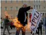  ?? AP ?? A Syriza party flag being burned outside the Greek Parliament during a rally in Athens. —