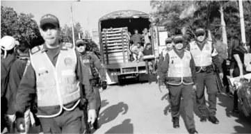  ??  ?? Venezuelan­s ride on a truck escorted by police officers during an operation by the Colombian police to evict a community of homeless Venezuelan migrants from a sport centre, in Cucuta, Colombia. — Reuters photo