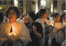  ?? Mark Schiefelbe­in / Associated Press ?? Worshipers hold candles during a Mass at the Cathedral of the Immaculate Conception, a government-sanctioned Catholic church in Beijing.