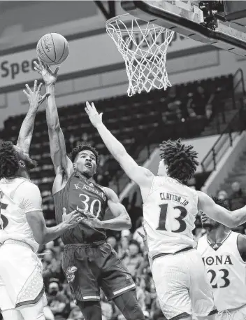  ?? Jacob M. Langston / Associated Press ?? Kansas’ Ochai Agbaji shoots against Iona’s Tyson Jolly, left, and Walter Clayton Jr. Agbaji had 17 points.