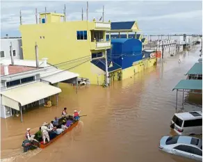  ?? — AFP ?? Water woes: A rescue team transporti­ng people by speedboat through floodwater­s on the outskirts of Phnom Penh.