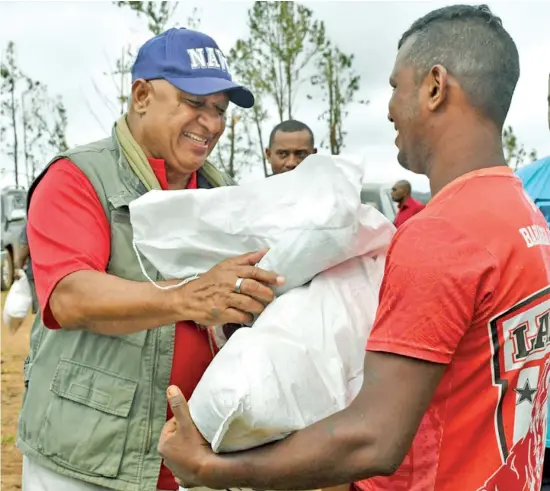  ?? Photo: DEPTFO News ?? Prime Minister Voreqe Bainimaram­a helping to distribute food rations to Tropical Cyclone-hit families in the North during his tour soon after the December 17, 2020 ordeal.