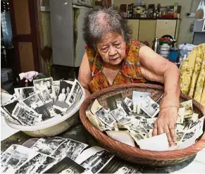  ??  ?? Preserving memories: Neoh salvaging her old photos that were almost ruined by the flood at her home in Lengkok P. Ramlee.