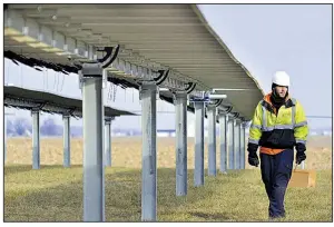  ?? AP/JEFF MOREHEAD ?? A worker walks beneath solar panels being installed at Madison-Grant High School near Fairmount, Ind., on Dec. 21.