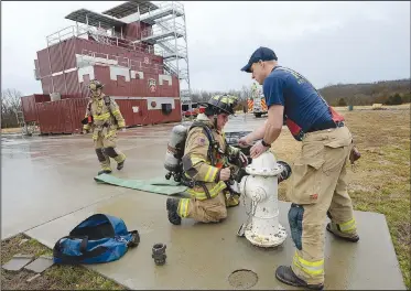  ?? NWA Democrat-Gazette/ANDY SHUPE ?? Marcus Mason (right) and Nathan Whitekille­r, both Fayettevil­le firefighte­rs, charge a fire hose Wednesday during high-rise firefighti­ng training at the department’s training facility in south Fayettevil­le. City voters will head to the polls April 9 to consider 10 bond questions totaling more than $226 million in projects. About $15 million is included for the Fire Department for three new fire stations, trucks and equipment.