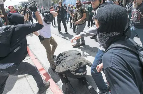  ?? Josh Edelson/AFP/Getty Images ?? A man crouching for cover, center, gets hit with a bike lock as multiple fights break out between Trump supporters and antiTrump protesters Saturday in Berkeley, Calif. Hundreds of people with opposing opinions on President Donald Trump threw stones,...