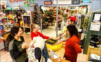  ?? PHOTO VINCENT OSUNA ?? sylvia castaneda (right) and her son David Varga help a pair of customers choose a selection of vintage records during the small Business saturday Pop up Market held saturday inside sylvia’s Little Treasures in Brawley.