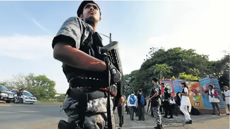  ?? Picture: JACKIE CLAUSEN ?? TRIGGER POINT: Armed guard Julian Reddy, of KZN VIP Protection Services, watches over pupils leaving Phoenix Secondary School