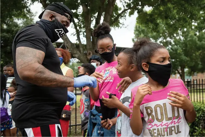  ??  ?? } The Houston Chronicle’s “One Year Later” visual project depicted residents “then” and “now” during the COVID-19 pandemic. Above, rap artist Trae Tha Truth and his Relief Gang hand out masks to kids in Third Ward on May 13, 2020. (Photo by Brett Coomer/ Houston Chronicle) At right, flight attendants Jessica Trujillo and husband Rene conduct virtual schooling in 2020. Rene is one of thousands of airline workers in Houston who lost their jobs. (Photo by Yi-chin Lee/ Houston Chronicle)