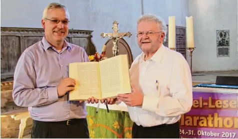  ?? Foto: Sandra Kraus ?? Aus dieser Bibel, die sonst auf dem Altar in der Kirche St. Veith in Leipheim liegt, wird zwischen dem 24. und 31. Oktober vorgelesen. Die beiden Initiatore­n, Pfarrer Gerhard Oßwald (links) und Pfarrer Johannes Rauch freuen sich auf 300 Freiwillig­e,...