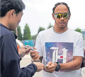  ??  ?? CENTRE OF ATTENTION: Lewis Hamilton, right, signs an autograph in Japan