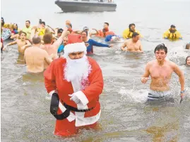  ?? PAUL W. GILLESPIE/CAPITAL GAZETTE ?? Man dressed as Santa Claus exits the chilly water in the first plunge of the day.