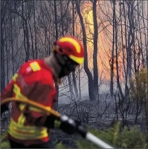  ?? AP/PAULO DUARTE ?? Portuguese firefighte­rs work to stop a forest fire from reaching the town of Figueiro dos Vinhos on Sunday in central Portugal.