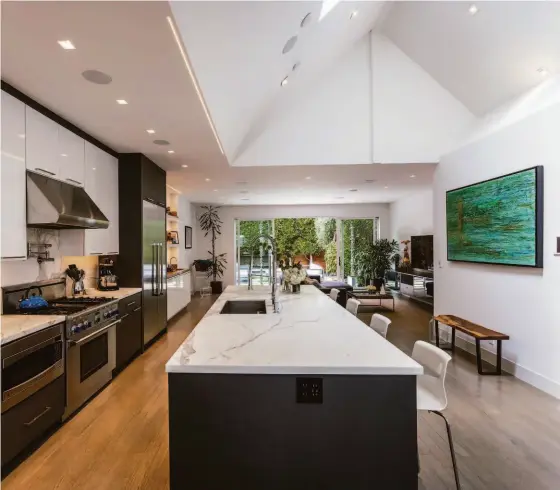  ?? KENT JOHNSON/IVC STUDIO ?? The open concept kitchen features profession­al-grade appliances and a large island illuminate­d by a mudded-in ceiling LED bar.