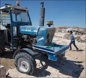  ?? ?? A boy runs Sept. 30 by a tractor with a shattered windshield and flat tires following the attack.