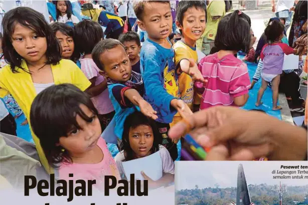  ?? [ FOTO REUTERS ] ?? Kanak-kanak sekolah mendapat pensil warna ketika hadir ke sekolah di sebuah kem untuk mangsa yang dipindahka­n akibat gempa dan tsunami di Palu, semalam.