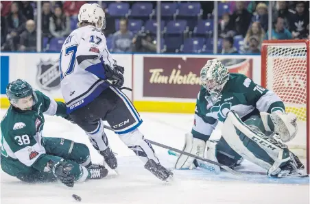  ??  ?? Victoria Royals’ Tyler Soy cuts in front of the net between Everett Silvertips’ Kevin Davis and goaltender Carter Hart on Saturday night.