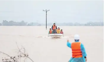  ?? — AFP photos ?? Rescue personnel carrying villagers in a boat through floodwater­s in central Vietnam’s Ha Tinh province.