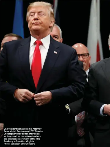  ??  ?? US President Donald Trump, Attorney General Jeff Sessions and FBI Director Christophe­r Wray button their coats as they stand for the national anthem at a graduation ceremony at the FBI Academy in Quantico, Virginia. Photo: Jonathan Ernst/Reuters