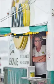  ?? PHOTO BY SEAN ELLIOTT/THE DAY ?? Lisa Silva watches the rain fall from the cover of the Del’s Frozen Lemonade truck parked on City Pier in New London on the opening day of Sailfest.