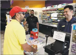  ?? JIM GENSHEIMER — STAFF PHOTOGRAPH­ER ?? Regular customer Jaswider Baria, at left, checks his lottery ticket number and buys another ticket from Ruby Singh.