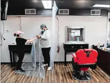  ?? SEAN D. ELLIOT/THE DAY ?? Raychelle Rivera, left, and owner Danny Garcia of I Got You Next Barbershop in Groton attach hangers on a shower curtain as they work to hang barriers between work stations Friday in preparatio­n to reopen.