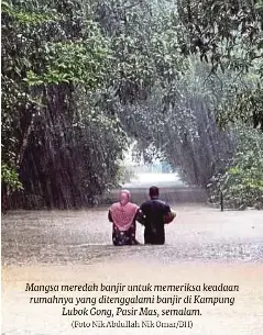  ?? (Foto Nik Abdullah Nik Omar/bh) ?? Mangsa meredah banjir untuk memeriksa keadaan rumahnya yang ditenggala­mi banjir di Kampung Lubok Gong, Pasir Mas, semalam.
