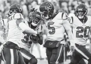  ?? Brett Coomer / Staff photograph­er ?? Terrance Mitchell, second from left, celebrates with Tyrod Taylor (5) and Lonnie Johnson Jr., left, after getting one of the Texans’ four intercepti­ons of the Titans’ Ryan Tannehill on Sunday.