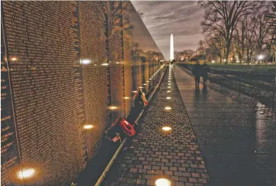  ?? PHOTOS BY DENNIS BRACK ?? After losing the 1992 election just days before, the first couple arrived at the Vietnam Veterans Memorial — unaccompan­ied — where late night volunteers were taking turns reading aloud the names of all 58,183 brave souls inscribed on “the Wall.”