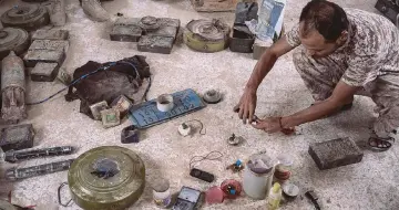  ??  ?? A specialist in bomb disposal kneels near explosive devices made by Al-Qaeda militants.