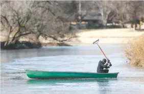  ?? FERNANDO SALAZAR/THE WICHITA EAGLE VIA AP ?? Tim Christmore uses a rake to get his canoe through the ice-covered Little Arkansas River in Wichita, Kan., on Tuesday.