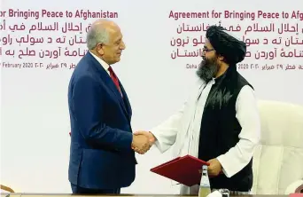  ??  ?? Stretta di mano tra l’americano Zalmay Khalilzad e il mullah Abdul Ghani Baradar, leader talebano, dopo l’accordo in Qatar