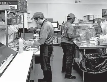  ?? TERESA CRAWFORD/AP PHOTOS ?? William Burns, left, general manager of the B. GOOD “ghost kitchen” at Kitchen United in Chicago, prepares an order.