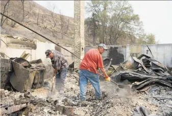  ?? Stephen Brashear / Getty Images ?? Rich Pitkethly and Randy Loucks dig through the remains of a home destroyed by a wildfire in the town of Pateros, Wash. The Carlton Complex of fires has burned 243,000 acres.