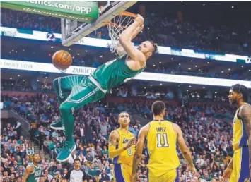  ??  ?? The Celtics’ Aron Baynes hangs from the rim after dunking during the fourth quarter Wednesday night in Boston’s 107-96 victory over the Los Angeles Lakers.