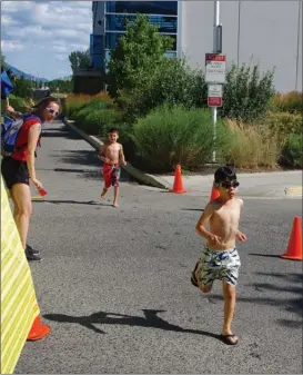  ?? BARB AGUIAR/Special to The Daily Courier ?? Race director Tara Melville directs kids running from the pool to the cycling section of the SunRype TriKids triathlon at the H2O pool and the Mission Sports Fields Sunday.