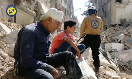  ??  ?? In this file photo provided by the Syrian Civil Defense group known as the White Helmets, residents sit amongst rubble in rebel-held eastern Aleppo, Syria